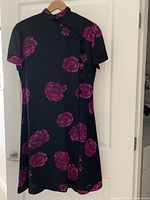 Full view of the black dress with large purple flowers and mandarin collar showing the garment style and floral pattern