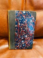 Front cover of the 1836 book showing marbled red, blue, black, and white pattern with black leather spine and corners