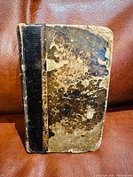Front cover of Bible dictionary book showing worn, aged brown cover with black spine