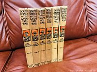 Six volumes of "South Africa and the Transvaal War" by Louis Creswick, lined up on a couch showing their spines with titles and illustrations.
