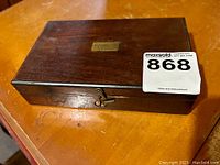 Closed wooden box with a brass plaque and visible lock hardware