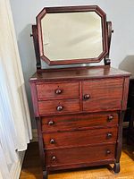 Front view of antique Empire style highboy chest with four drawers and matching tilt mirror attached on top.
