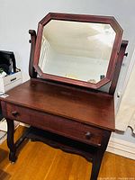 Front view of antique wood vanity desk with attached swivel mirror showing drawer and surface.