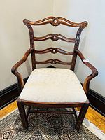 Front view of antique George III style mahogany armchair showing carved pierced ladder back and upholstered seat.