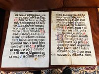 Two vellum manuscript pages side by side showing illuminated initials and black Latin text on vellum with aged but excellent condition.