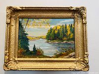 Full view of oil on board painting in gold ornate frame showing landscape scene with river and trees.