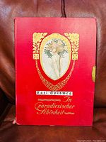 Front cover of red folio with gold lettering and floral design by Carl Spitzweg