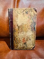 Front cover showing marbled pattern with worn areas and aged leather spine edges.