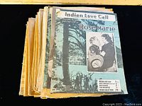 Stack of antique sheet music featuring colorful covers including 'Indian Love Call' and 'Rose Marie'