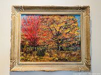 Framed fall landscape painting showing vibrant autumn trees with a wooden fence under blue sky.