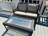 Full view of dark brown wicker loveseat and coffee table on deck