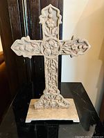 Frontal view of the ornate cast iron cross showing detailed floral and grape motifs and weathered finish.