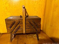 Closed wooden vintage sewing basket with fold-out compartments and handle