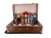 Open brown textured suitcase with 7 dolls standing inside, showing various colorful outfits from 1980s era