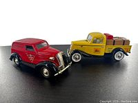 Two diecast metal coin banks side by side, red Canadian Tire van and yellow Home Hardware pickup truck on display surface