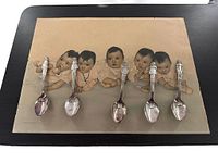 The vintage Dionne Quintuplets print displayed with five collector spoons arranged on top, showing the print and the spoons together.