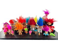 Large collection of vintage Russ troll dolls arranged in a row showing variation in sizes and hair colors including reds, pinks, yellows, and blues