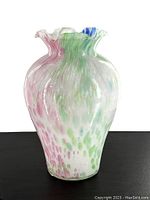 Front angle showing multicolor splashes in pink, green, blue with ruffled top and bulbous body