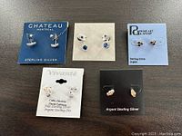 Photo of all 7 pairs of sterling silver earrings arranged on five branded display cards