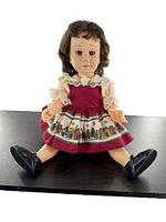 Full front view of doll seated with legs spread, showing outfit and shoes