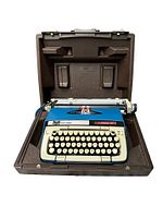 Smith Corona Classic 12 blue typewriter inside the open brown hard carry case shown from front angle, entire unit visible