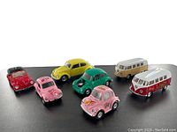 Lot of six vintage style Volkswagen toy vehicles on a black background displaying their colors and designs.