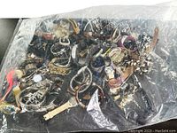 Top view of bag containing multiple vintage watches with various strap types and colors seen through transparent bag.