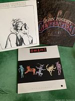 Three LPs displayed showing front covers of Robert Palmer's 'Secrets', Heart's 'Bad Animals', and John Fogerty's 'Centerfield' albums.