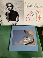 Photo showing three vinyl LP records: Van Morrison's 'Wavelength', John Lennon's 'Imagine', and Dire Straits' 'Brothers in Arms' albums.