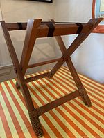 Wooden folding suitcase stool with woven feet and diagonal cross leg design.
