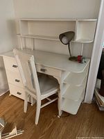 View of entire desk and chair from side angle showing shelving, drawers, lamp and pencil sharpener