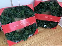 Two boxed green pre-lit Christmas wreaths, 30 inches diameter each, in red and white Astiari branded boxes.