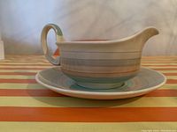 Side view of Susie Cooper gravy boat on matching saucer showing color and shape details
