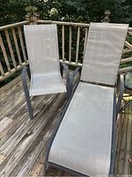 Photo of an outdoor chaise lounge and chair on a wooden deck. Both have dark metal frames and light-colored webbed seating and back supports.