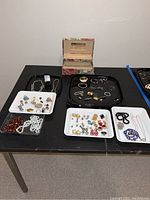 Full view of the lot displayed on table: trays holding necklaces, earrings, rings and jewelry box