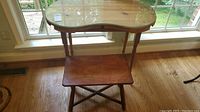Wooden desk with curved shape glass protector top and wooden legs, showing the top surface and legs.