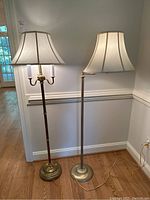 Two brass toned floor lamps shown side by side with matching fabric bell-shaped shades, both approximately 59 inches tall
