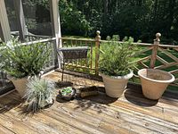 View of all plant containers on a wooden deck including vinyl planters, metal plant stand with plants, large ceramic bowl, small plastic planters, metal planter, and ceramic vase.