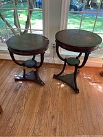 Photo showing the pair of vintage round side tables with leather tops and wooden tripod bases placed near window.