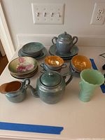 Full set showing tea set items and luncheon plates stacked, with the sadeite vase to the right.