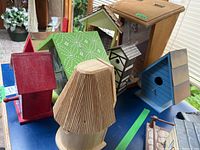 Overview of nine assorted bird houses and feeders in various colors and styles, shown on a blue table surface.