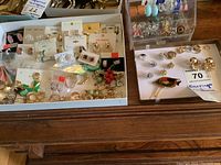 Full view of earrings spread in trays showing clip-on and pierced styles, some on branded cards
