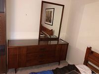 Front view of Mid-Century Modern wooden dresser with attached mirror and glass top.