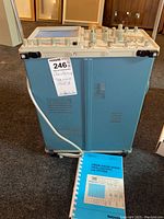 Full front and side view of the Tektronix oscilloscope with a manual booklet placed beside it.
