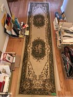 Traditional floral runner rug laid on hardwood floor surrounded by books and other items