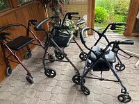 Three seated walkers positioned in a row showing their frames, wheels, seats and handlebars.