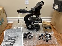 Front view of Wild Heerbrugg M20 microscope with incident light source, accessories laid out around it, and user manual.