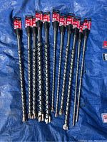 12 spiral flute bits laid on blue tarp showing lengths and tips