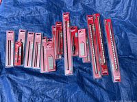 All Milwaukee hammer drill bits laid out on a blue tarp, showing variety in size and packaging.