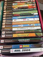 Image showing stacked PlayStation 2 game cases and discs with visible titles and some memory cards.